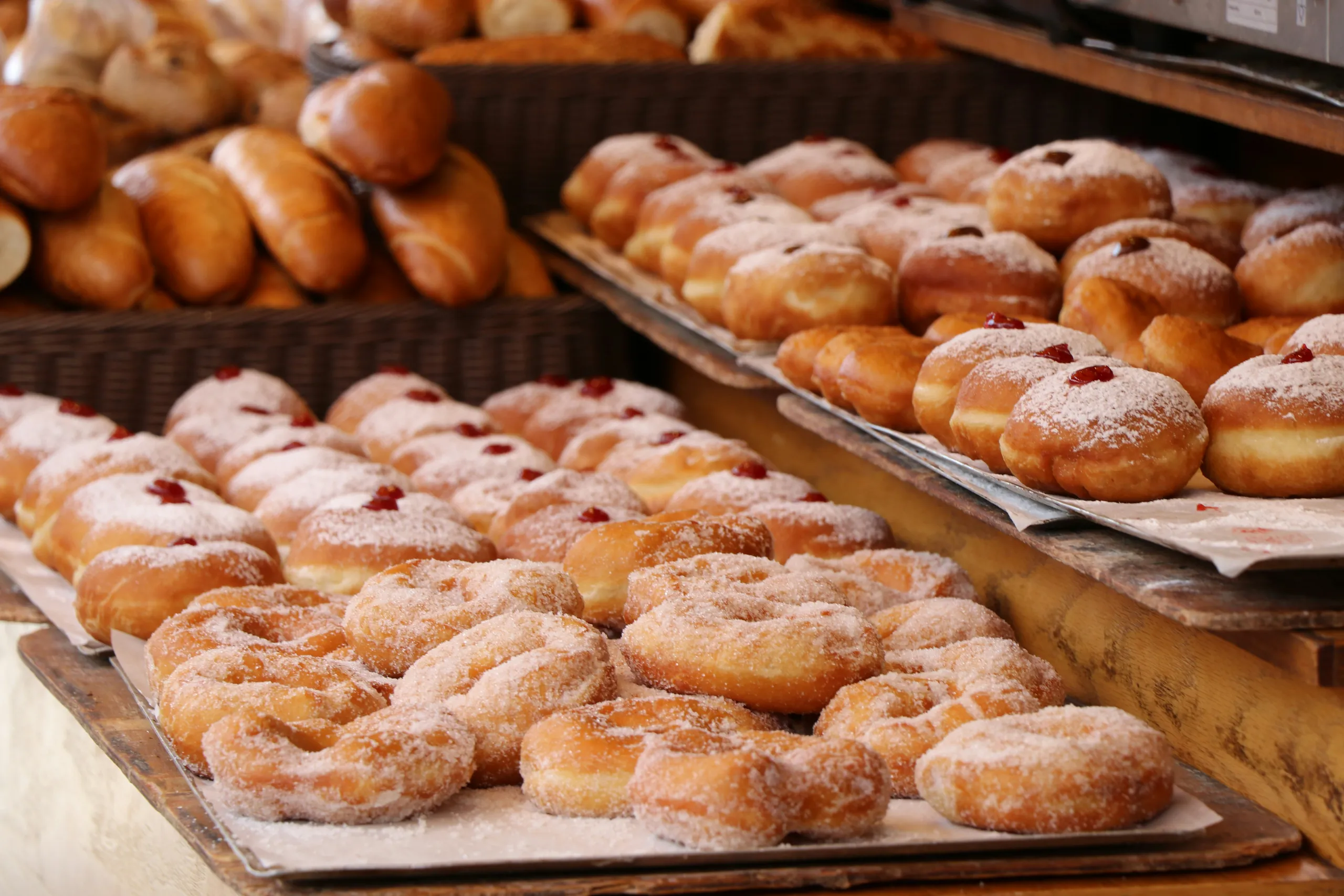 Donuts y bollos frescos espolvoreados con azúcar glas en bandejas de la panadería